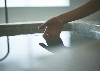 掛け流し上質なプライベートサウナ超軟水の水風呂をたしかめている女性の手