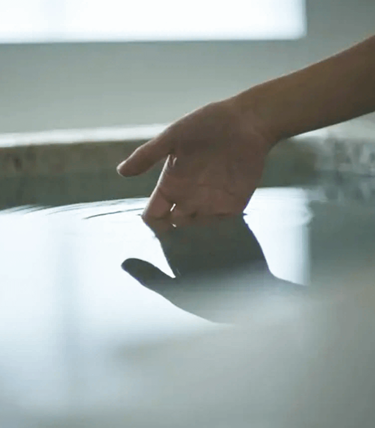 掛け流し上質なプライベートサウナ超軟水の水風呂をたしかめている女性の手