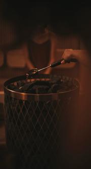 IKIサウナヒーターにロウリュ水をかける女性の手