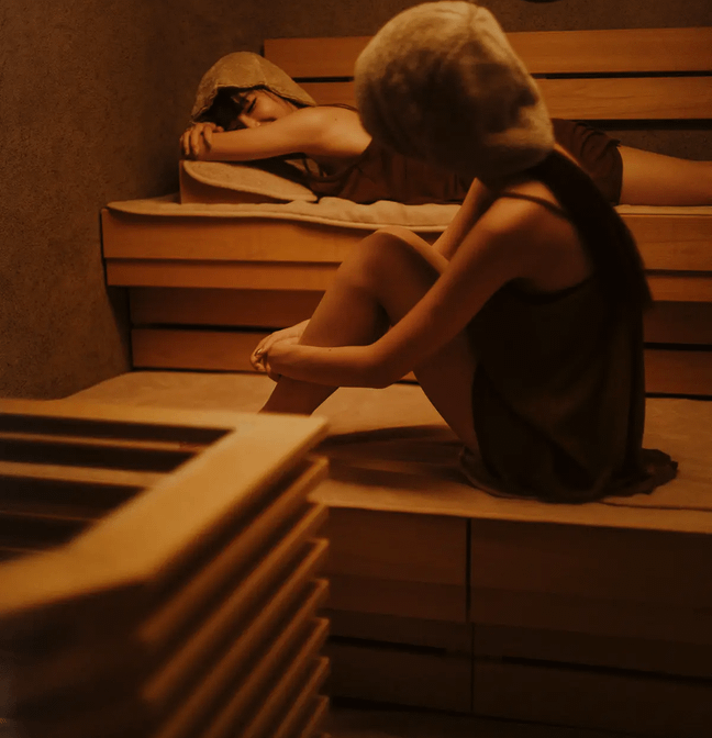 プライベートサウナのサウナルームで寝サウナしながら楽しむ女性二人