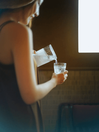 グラスに水を注ぐ女性