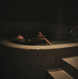 プライベートサウナルームの水深深い超軟水の水風呂につかる女性